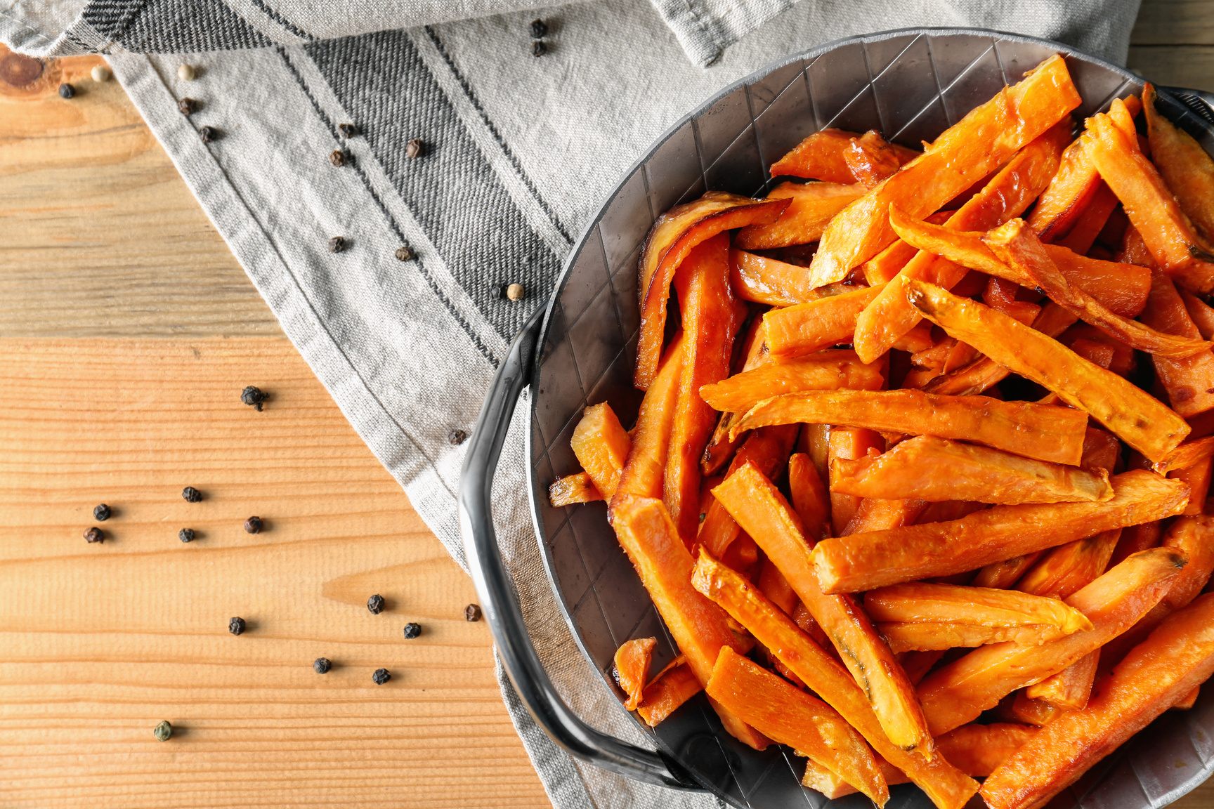 Pan with Sweet Potato Fries and Peppercorns on Wooden Table